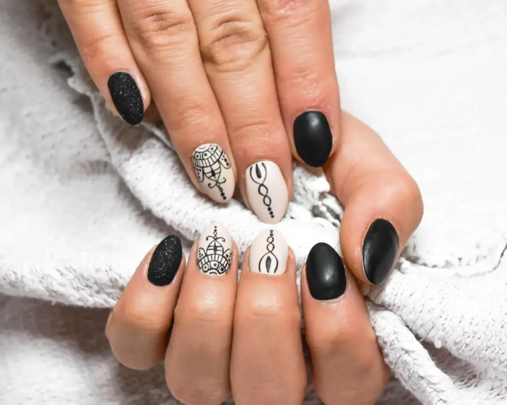 Naisen kädet Studio Lumossa, taidokkaasti koristellut musta-valkoiset kynnet – kynsitaide"